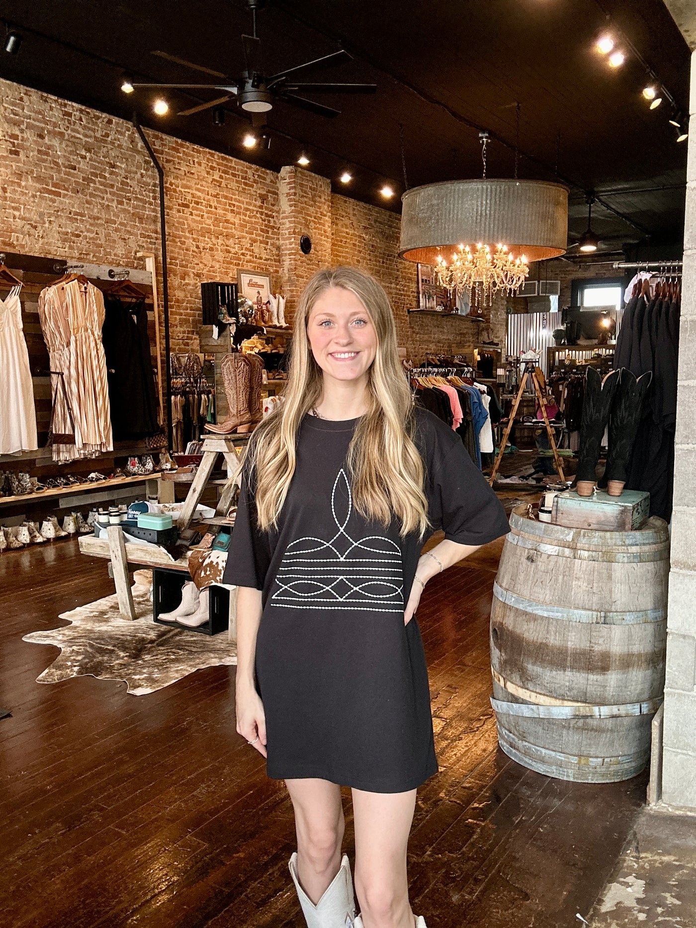 A Broker Leather employee modeling the black Brewer Boot-Stitch Graphic Tee Dress in our boutique.