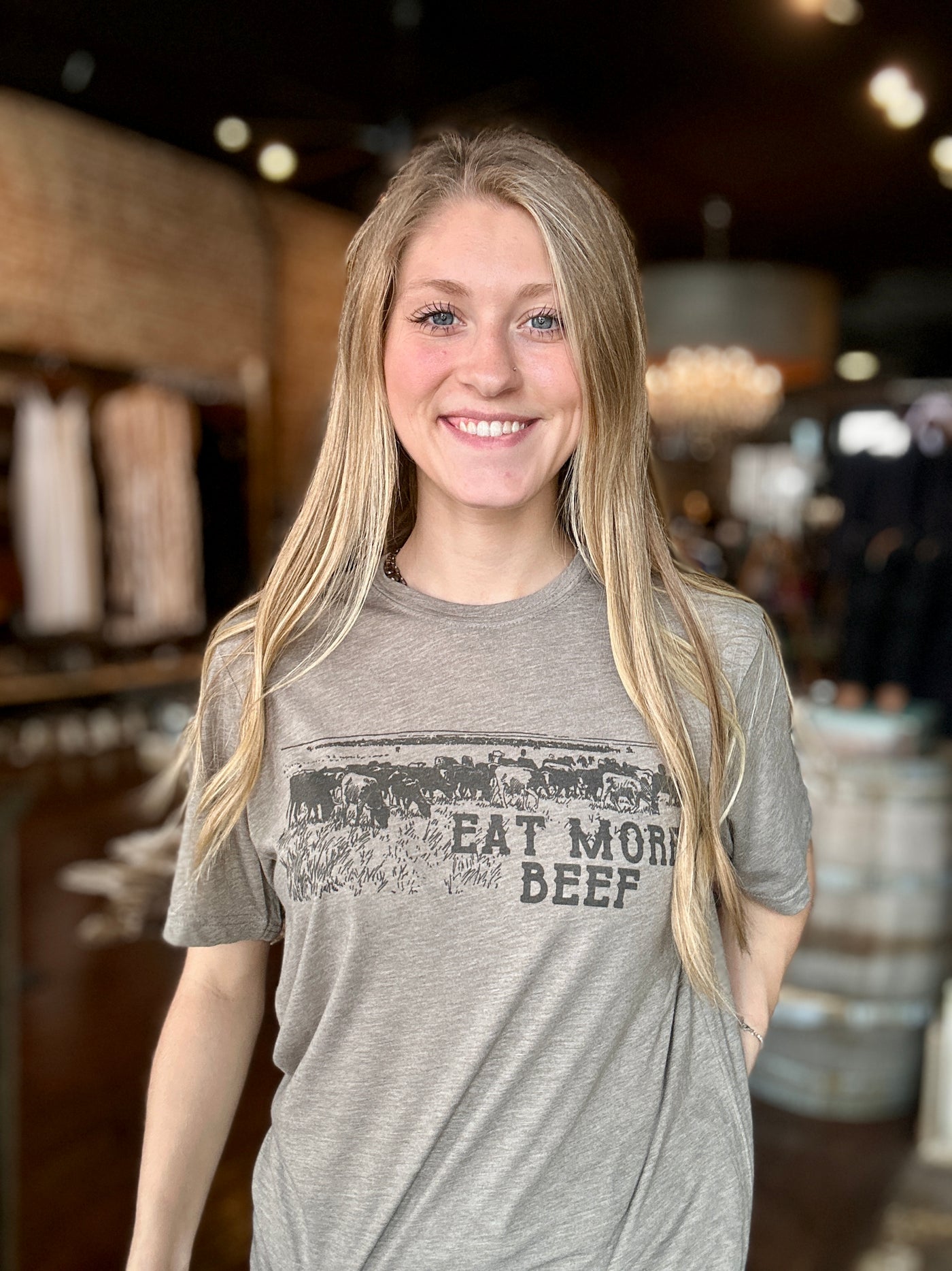 A Broker Leather employee modeling the Dinah Eat More Beef Graphic Tee in-store.