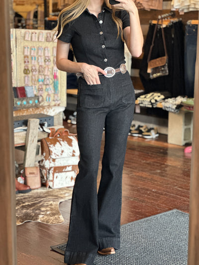 The Adalaide Genuine Leather & Concho Belt completes the look of a black denim jumpsuit on the Broker Leather Model.