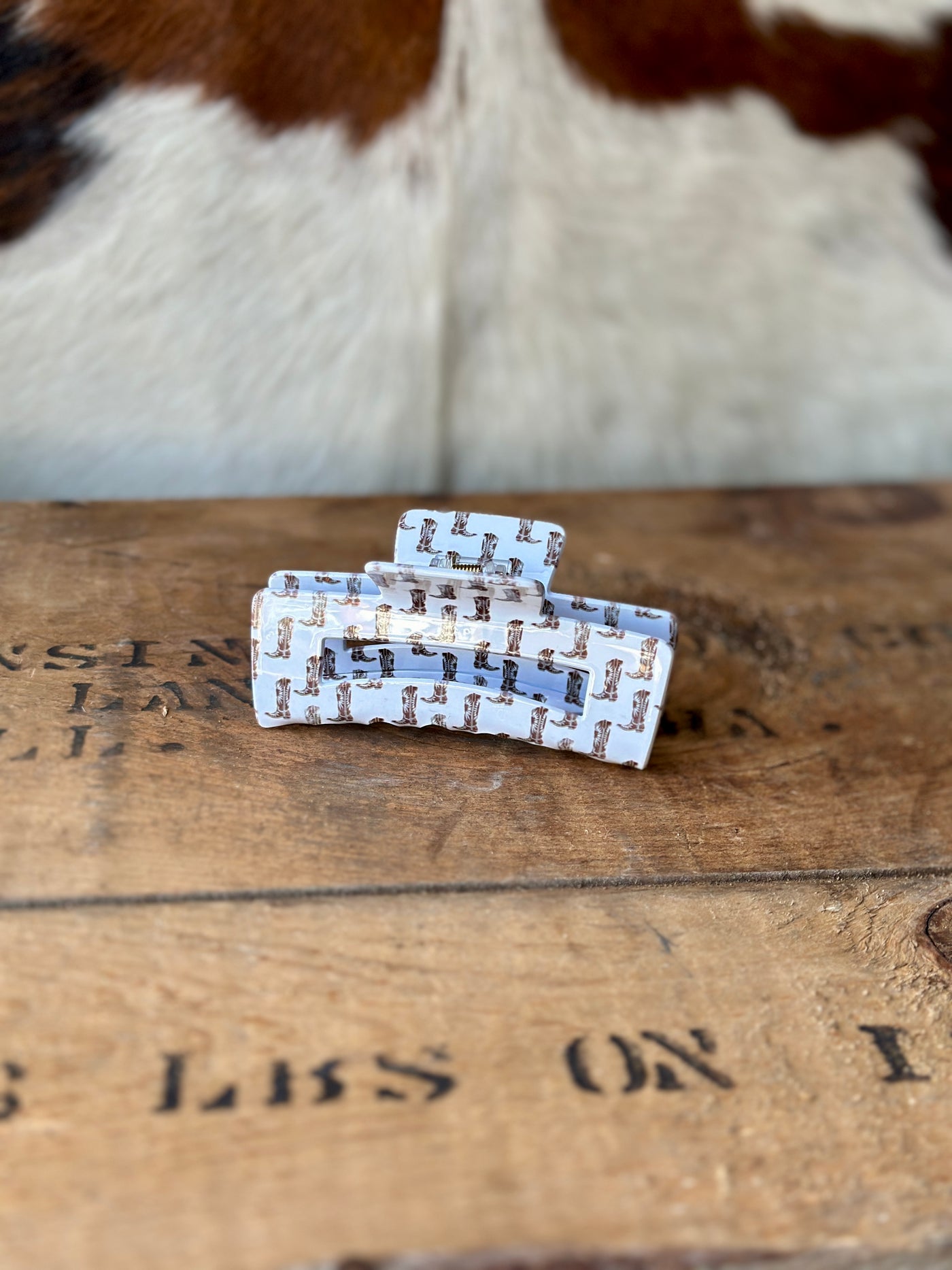 Side view of our Alisha Cowboy Boot Print Claw Clip on a wooden background.