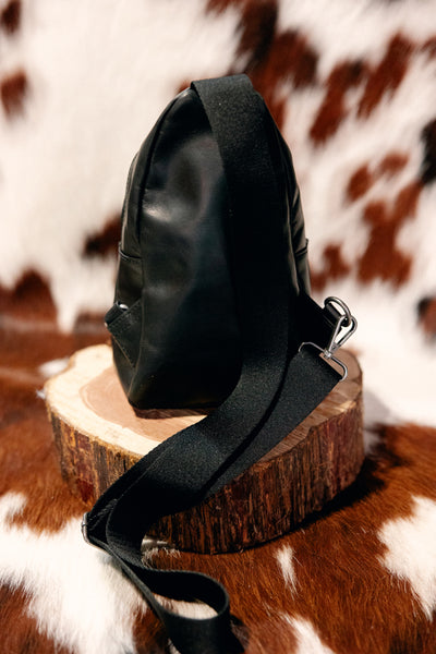 The Back view of the Ariat Casanova Sling Bag [Black] featuring an adjustable nylon sling strap.