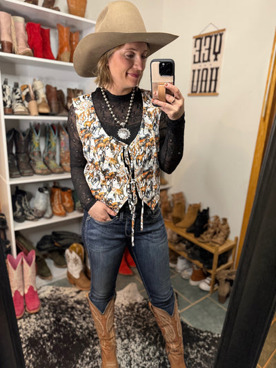 Mid-rise skinny Ariat jeans styled  with cowgirl boots, a horse-print top and cowboy hat.