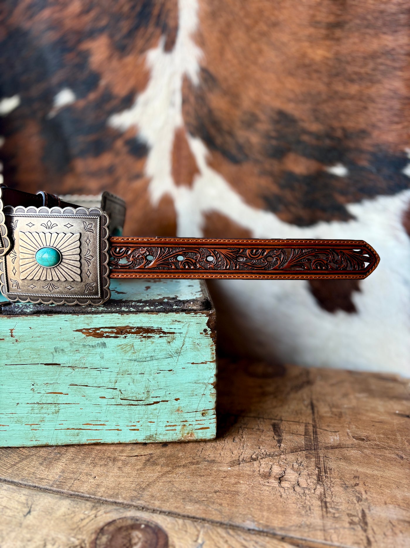 Close-up view of Ariat Tara Turquoise Concho Belt showcasing the intricate tooled leather portion of the durable belt.