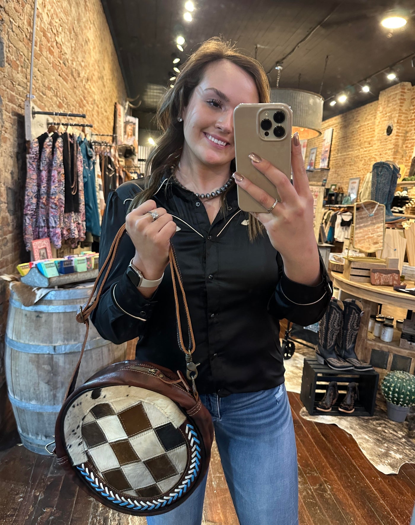 The Arlene Cowhide Bag held in a mirror selfie by Broker Leather employee, Gracelyn, demonstrating its size, versatility and statement-making capability in any setting.