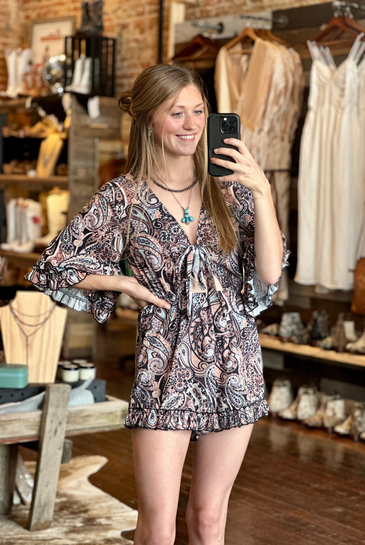 Woman modeling our Aurora Paisley Romper with vibrant paisley print and relaxed fit.