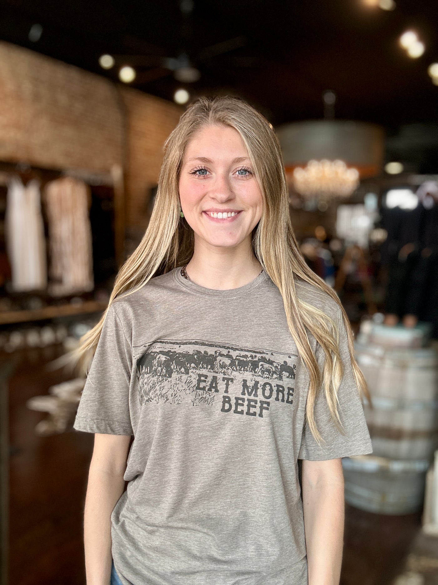 A Broker Leather employee modeling the Dinah Eat More Beef Graphic Tee in-store.