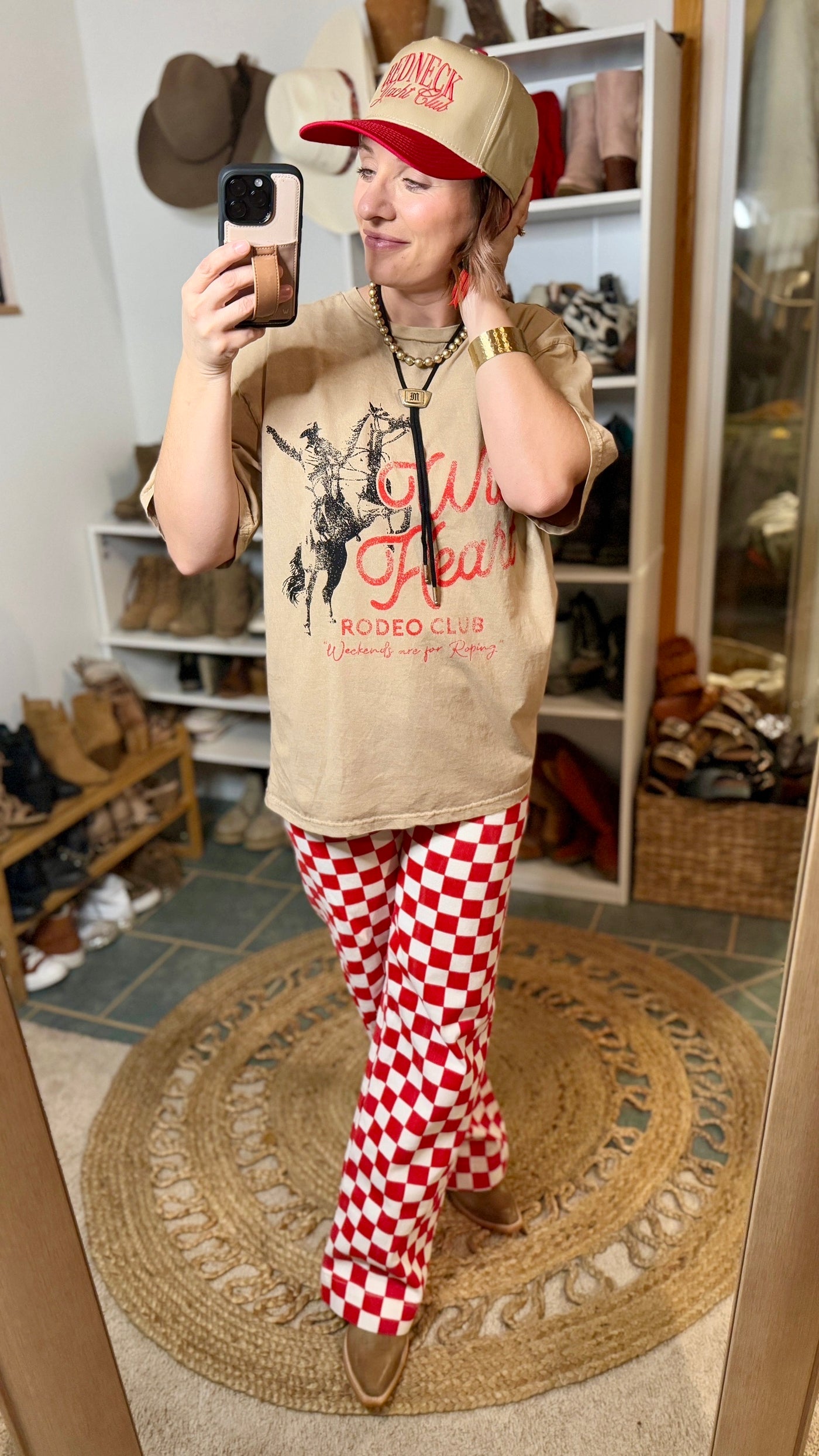 Styled outfit featuring the Bentlee Wild Heart Graphic Tee and trending checkered print pants, the Ariat Starlight boots, and a trucker hat.