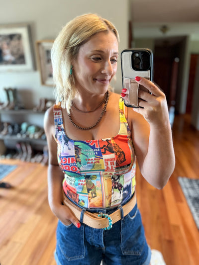 Woman taking a mirror selfie wearing a rodeo tank top and jeans showcasing a western leather belt and turquoise cluster belt buckle.