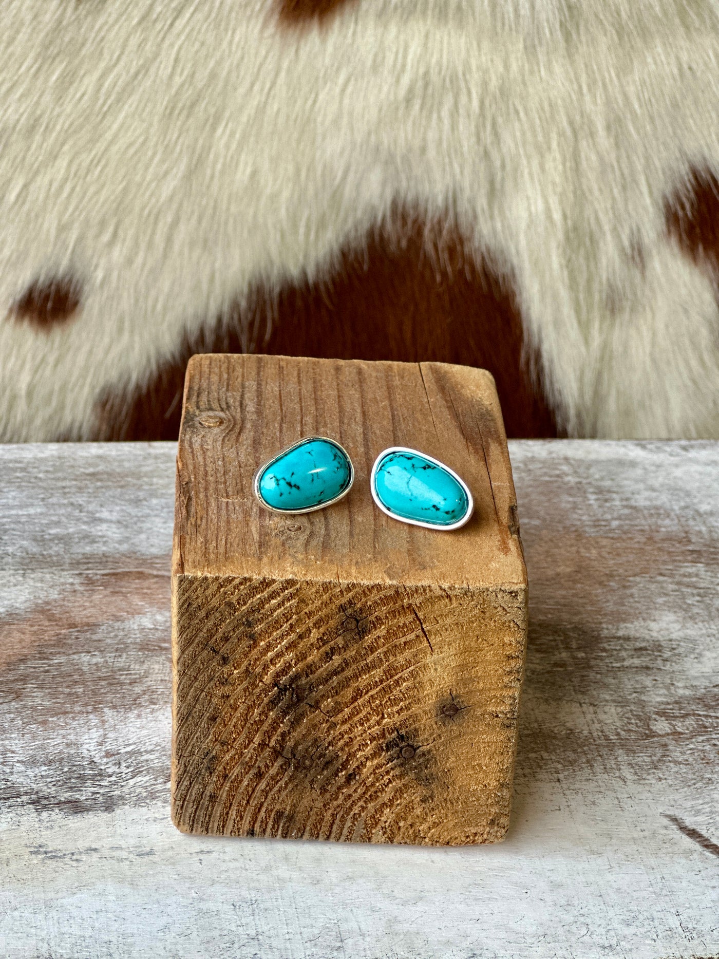 Close-up of Brandon Turquoise Nugget Stud Earrings on wood, showcasing unique stone variations.