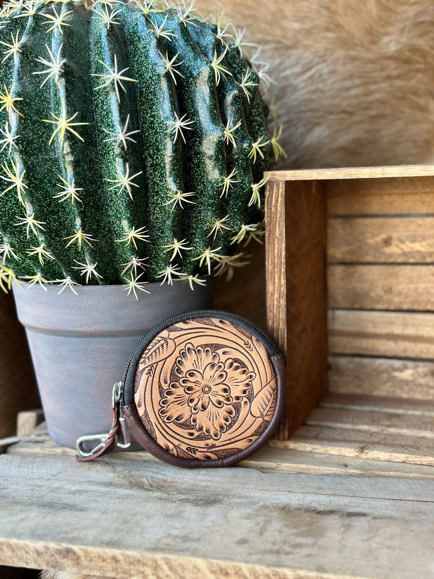 Western-style tooled leather coin purse with intricate craftsmanship and a secure zipper closure.