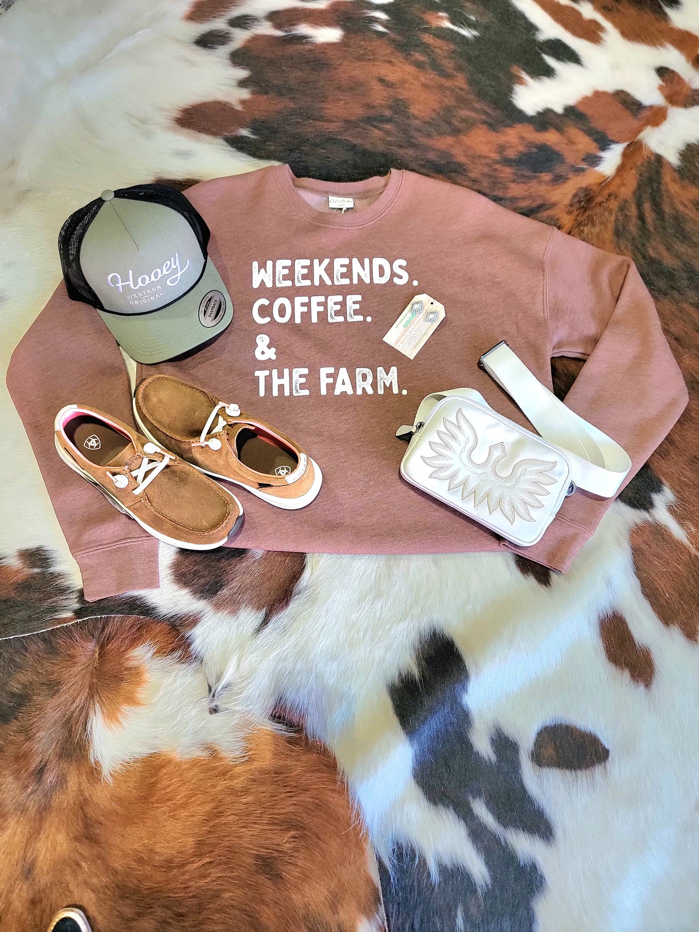 Outfit inspiration featuring Waterproof Ariat Brand Buckeye Slip-on Loafer Shoe [Weathered Honey Brown], the Hooey OG Cap [Olive Green & Black], a white crossbody bag, and earrings.