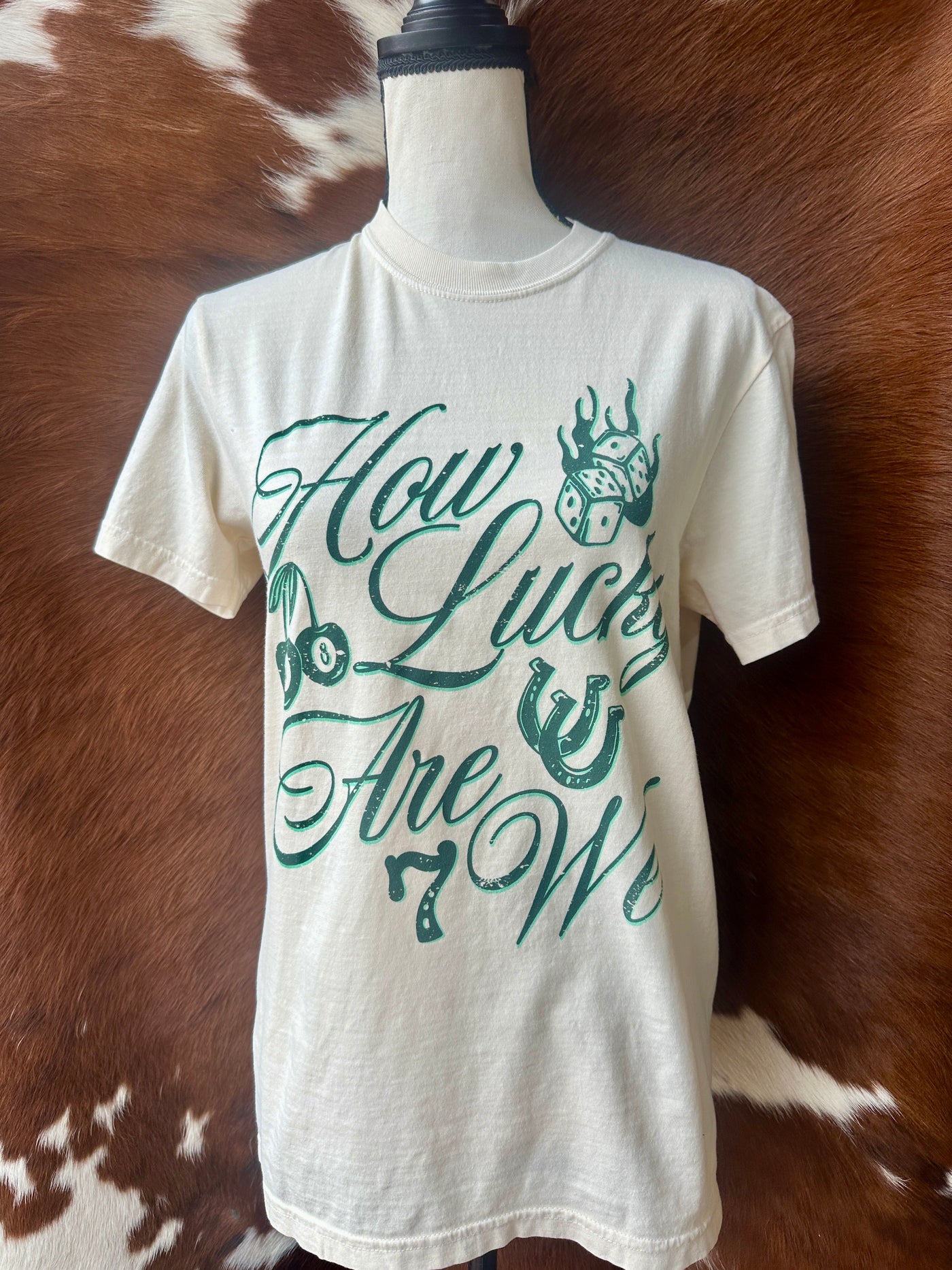 Close-up of the "Brianna How Lucky Are We" text, showcasing bold lettering and soft 100% cotton fabric.