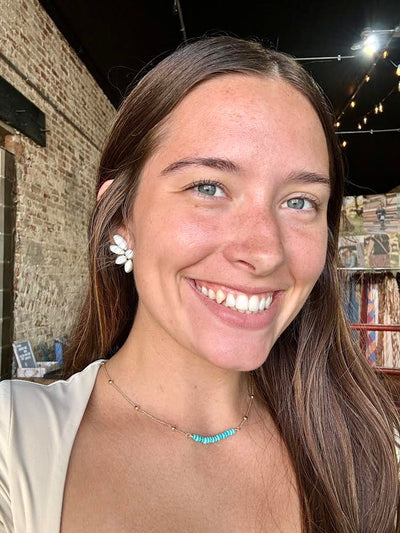 Britton White Buffalo Cluster Earrings with faux white buffalo turquoise stones on a silver-tone setting modeled by a Broker Leather employee.