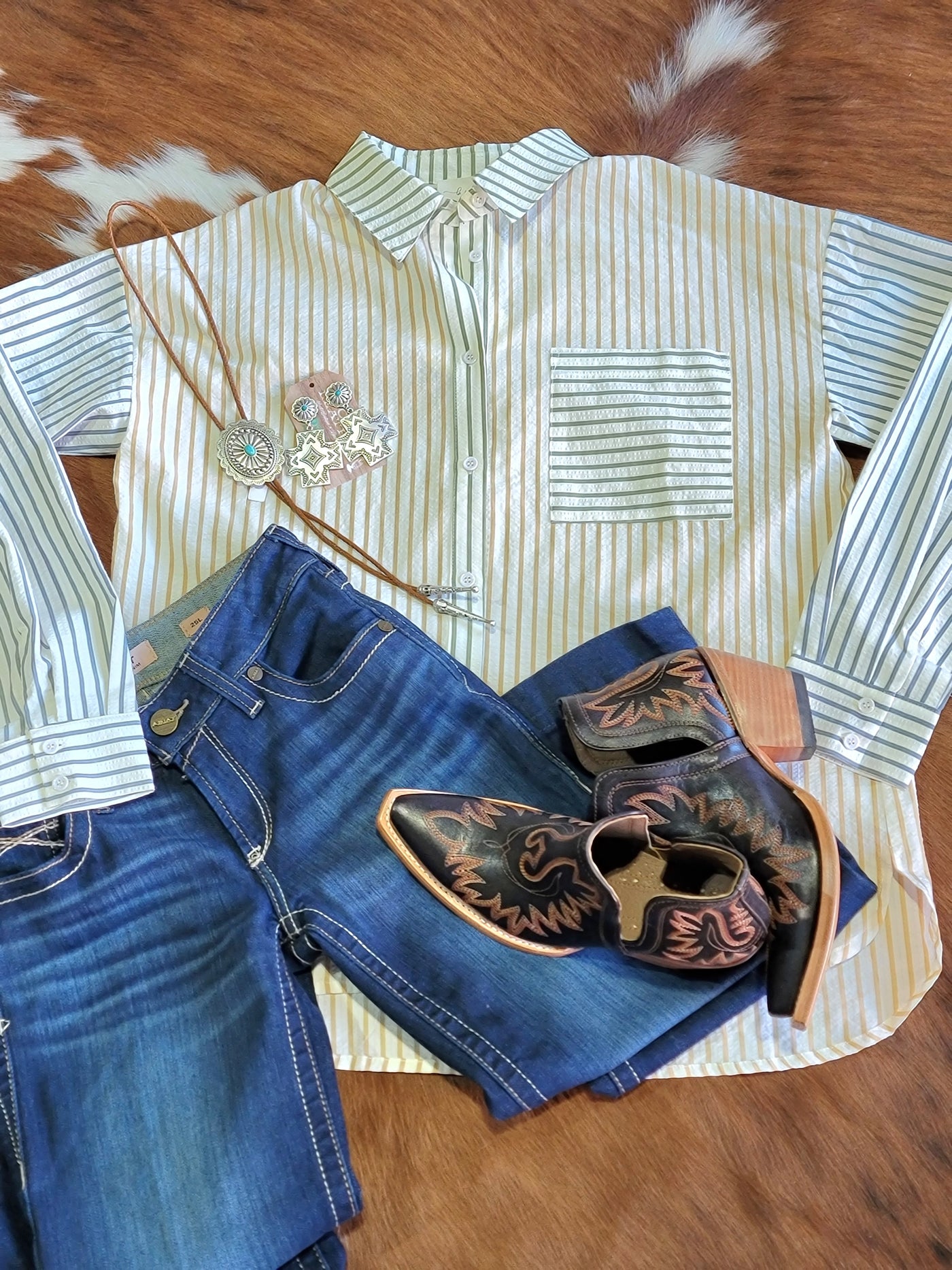 Flatlay of an outfit featuring a striped Button Down Blouse Shirt with jeans and boots.