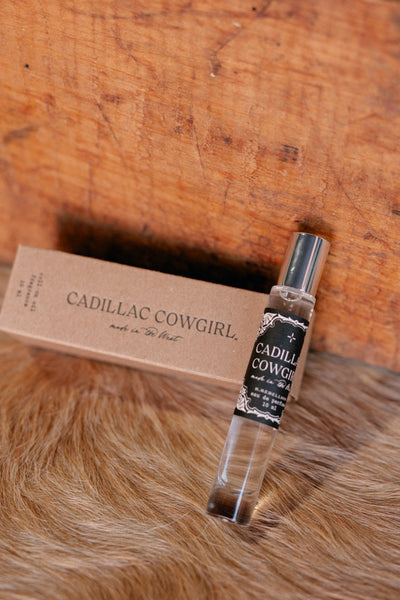 Photo of our glass roll-on bottle of Cadillac Cowgirl Perfume Oil with kraft box in background.