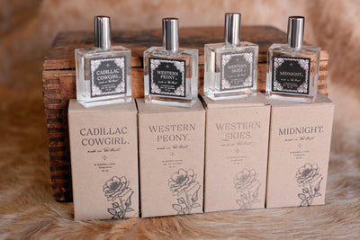 Photo of our set of Western Perfumes, specifically featuring our glass bottle of Cadillac Cowgirl Perfume Spray with kraft box.