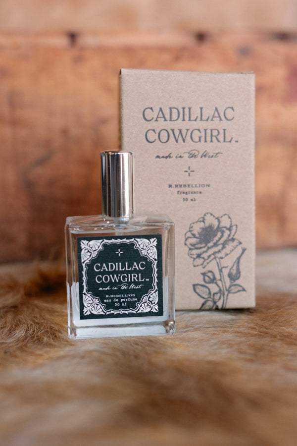 Close up view of our glass bottle of Cadillac Cowgirl Perfume Spray with kraft box in background.