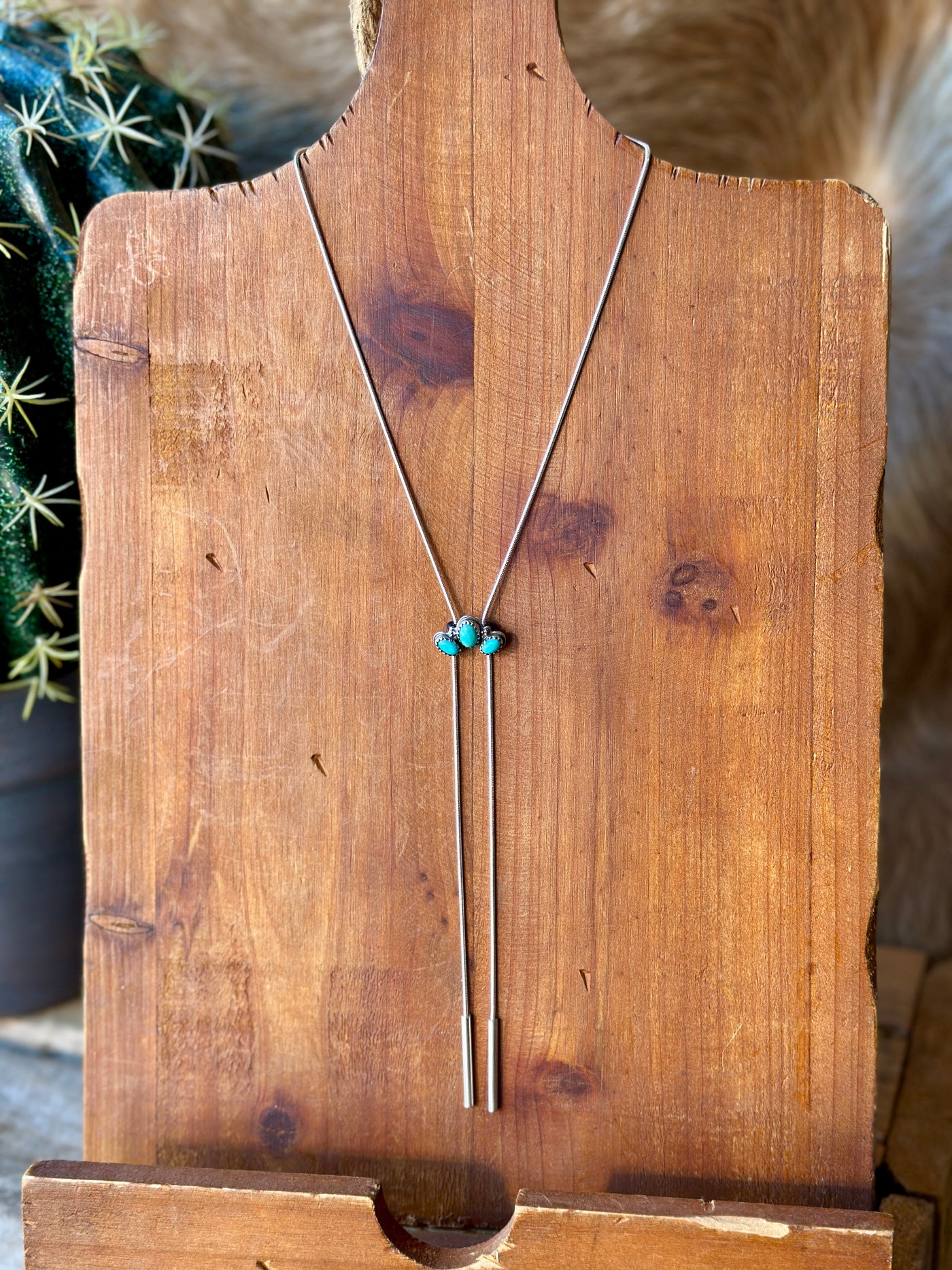 Handmade sterling silver bolo tie by Calvin, showcasing three turquoise stones in a half-cluster design, versatile adjustable length.