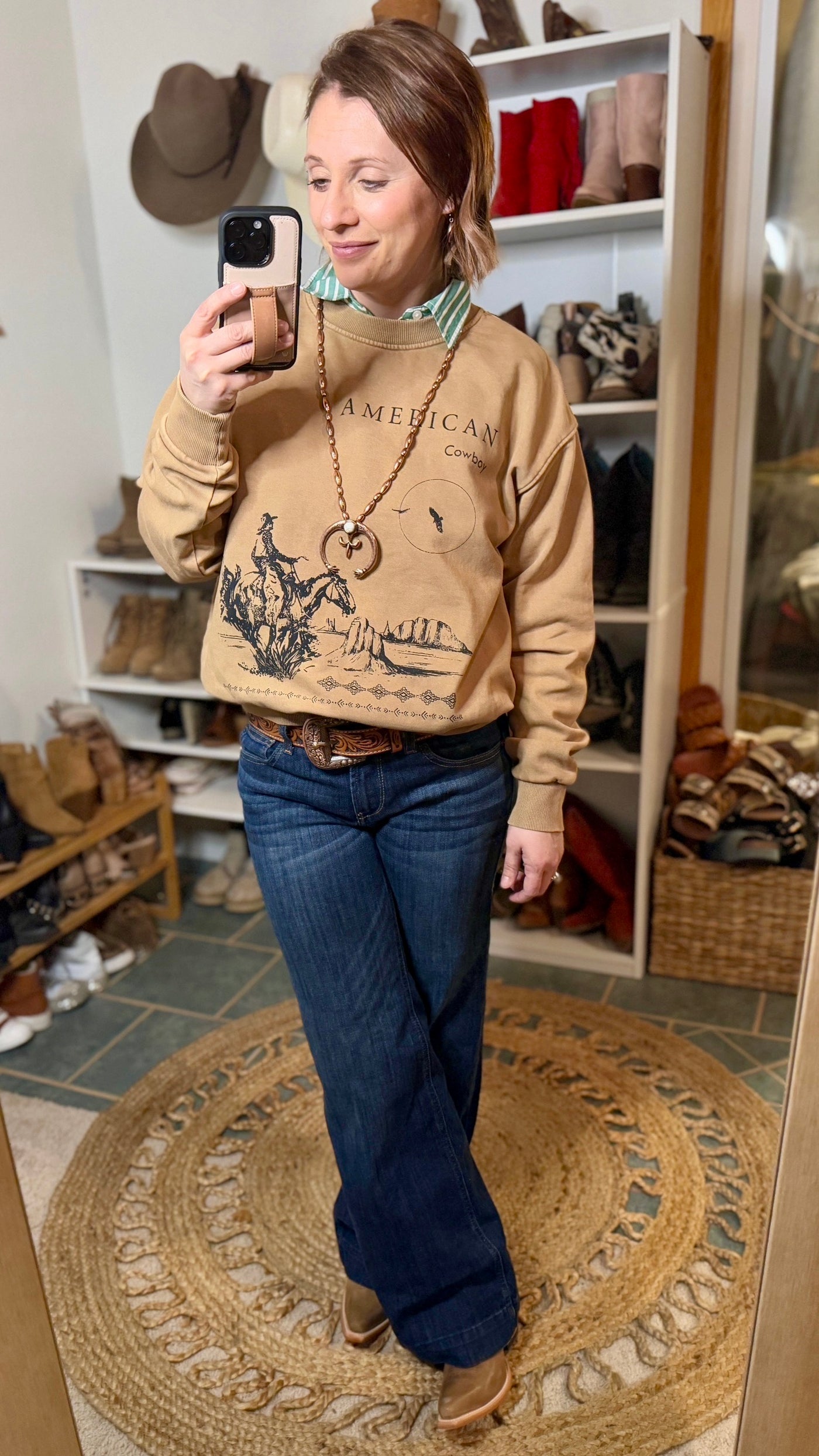 Model Wearing Chad American Cowboy Sweatshirt with Ariat Denim, the Ariat Starlight Boots, & the Dahlia Tooled Leather Belt.