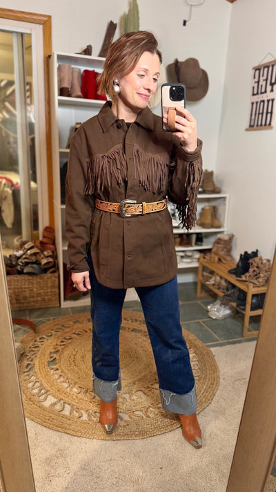 The Christy Tooled Leather Belt Styled  over a brown denim fringe jacket, Denim jeans and cowboy boots.