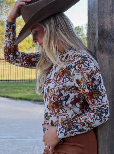 Clint Cowboys & Wild Horses Mesh Top featuring a white base with earthy tones of brown, orange, grey, and black, depicting cowboys lassoing wild mustangs.