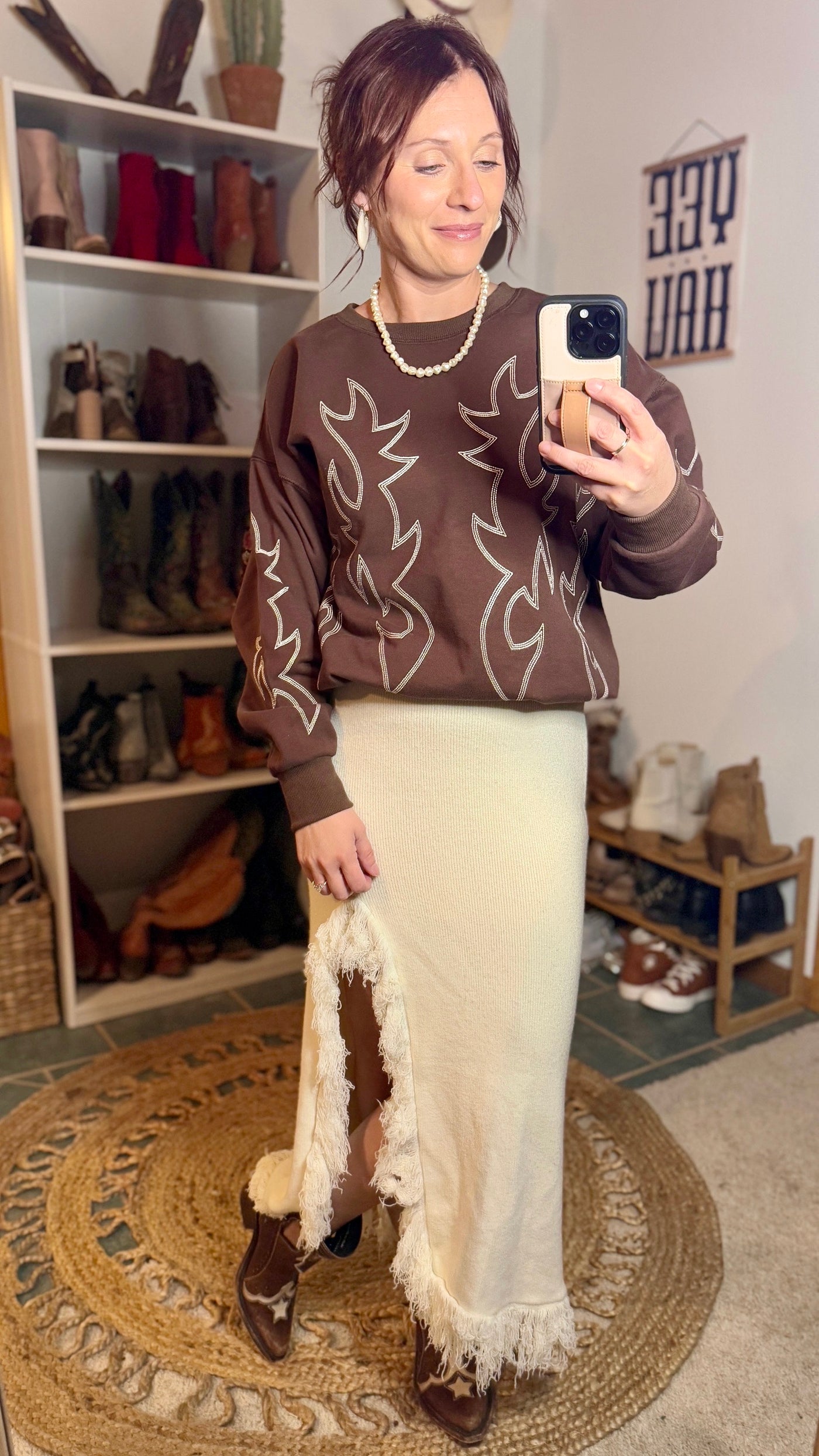 Brown boot-stitch pullover sweatshirt with a rustic western-inspired design modeled by Broker Leather Employee, Brooke.