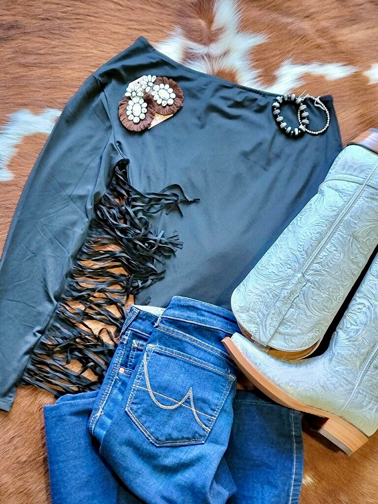 Sleek asymmetrical neckline and bold Western fringe on the Conway top, styled with high-waisted jeans and boots.