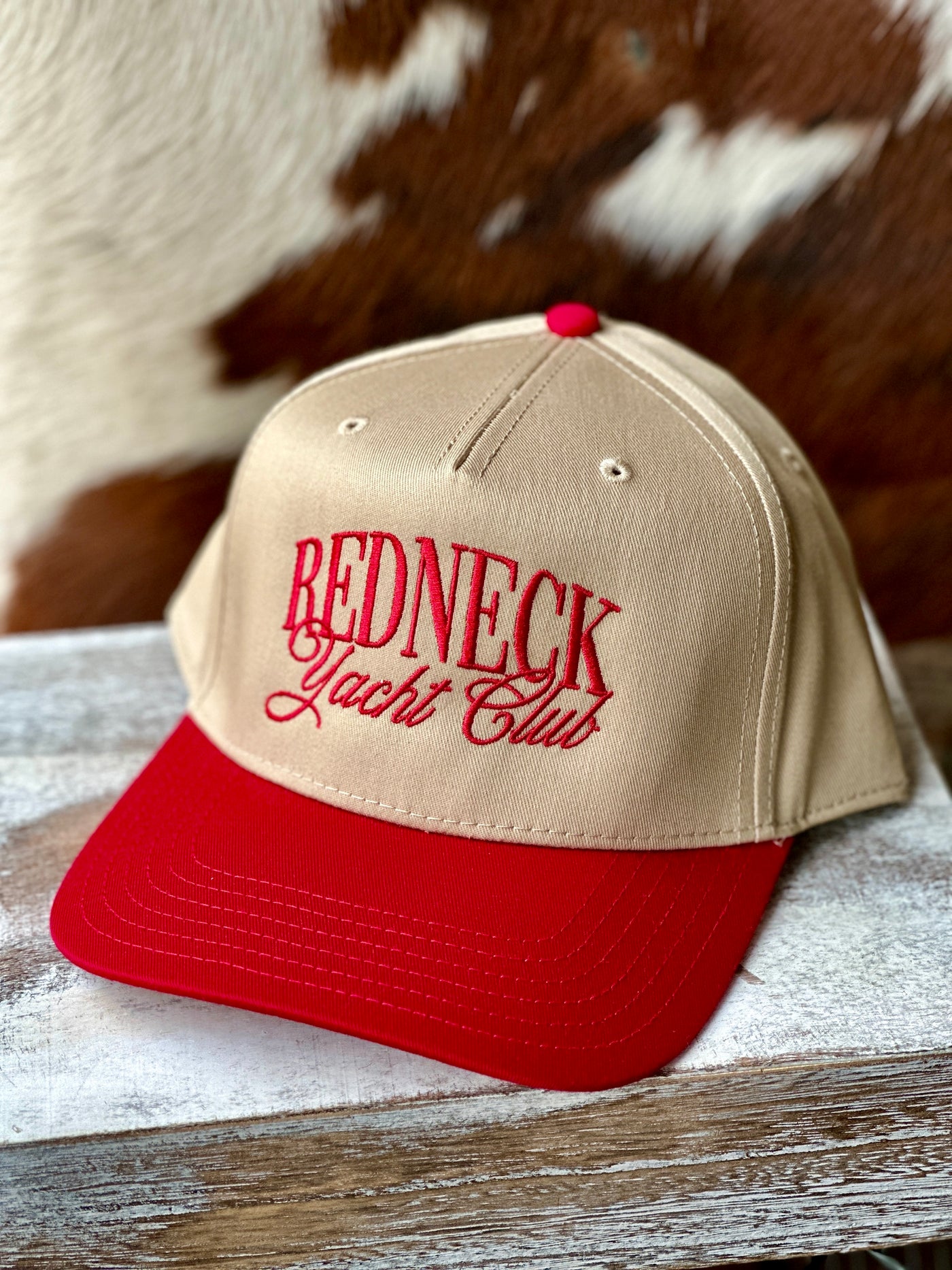 Front view of the Craig RYC Embroidered Baseball Cap, featuring bold red ‘Redneck Yacht Club’ embroidery on a natural tan base.