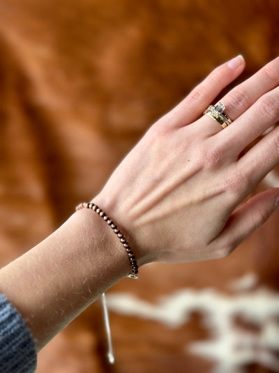 Sleek Crue Copper Navajo Pearl Bracelet, offering a warm copper glow to enhance glamorous holiday outfits.