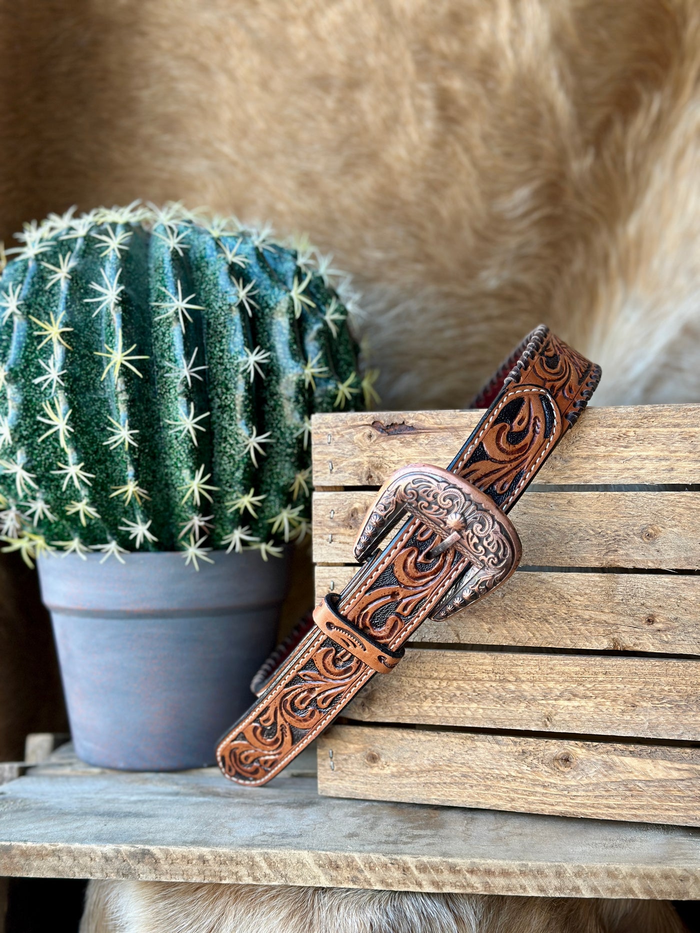 Black Dahlia Tooled Leather Belt with copper-colored engraved buckle, floral patterns, and brown whipstitch edging.