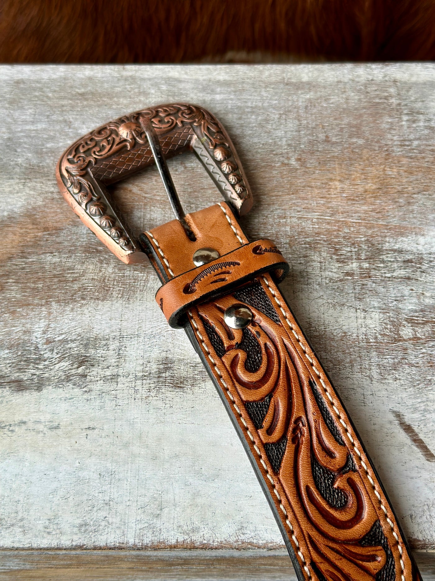 Close-up of Dahlia Tooled Leather Belt showcasing hand-tooled floral design and copper-colored buckle.