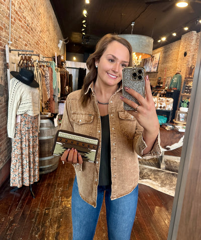 Boho-chic green and brown saddle blanket wallet with southwestern woven detailing and durable stitching held by woman for size relevance.