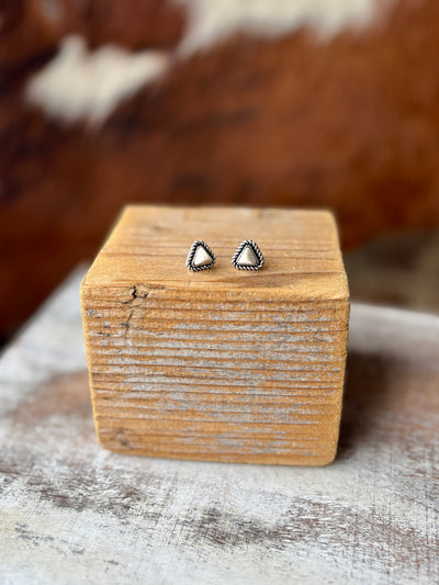 Western-inspired faux white buffalo stud earrings with intricate silver rope detail, displayed on wood.