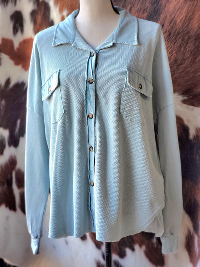 A fashionable waffle-like knit shacket in a soft powder/slate blue color with buttons.