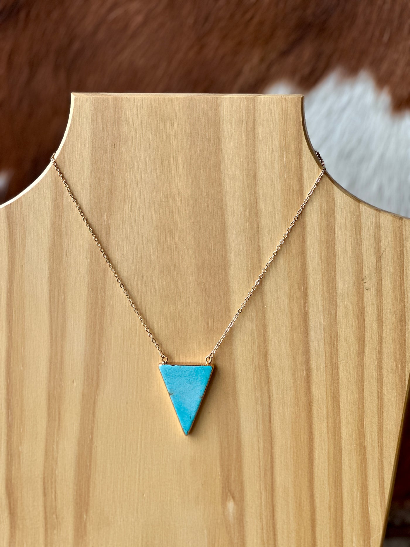 Close-up of triangle turquoise pendant with unique marbling and gold setting.