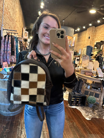 Fashionable and functional Dundee Cowhide Patchwork Backpack displayed by Broker Leather employee, Gracelyn, to show size.