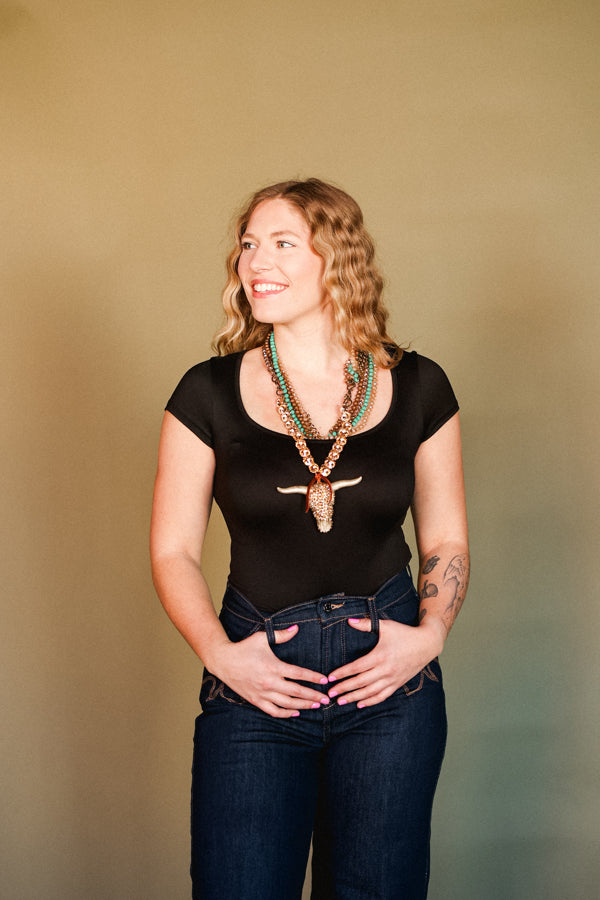 Woman modeling our Elliott Crystal Bull Skull Necklace with a black bodysuit.