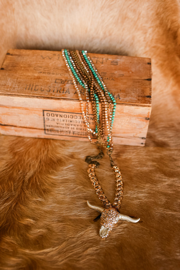 Flatlay of our Elliott Crystal Bull Skull Necklace on a wooden box.