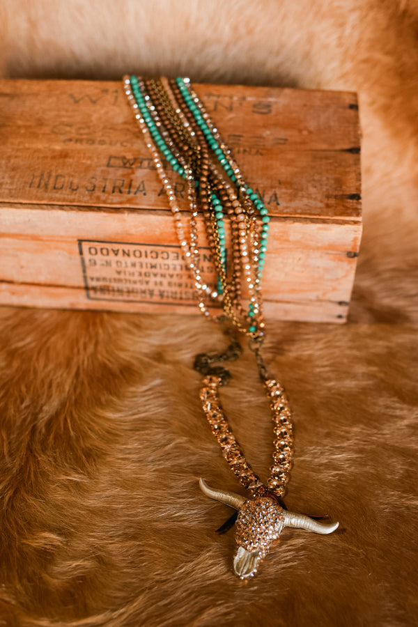 Elliott Crystal Bull Skull Necklace flatay photo on cowhide rug and wooden box.