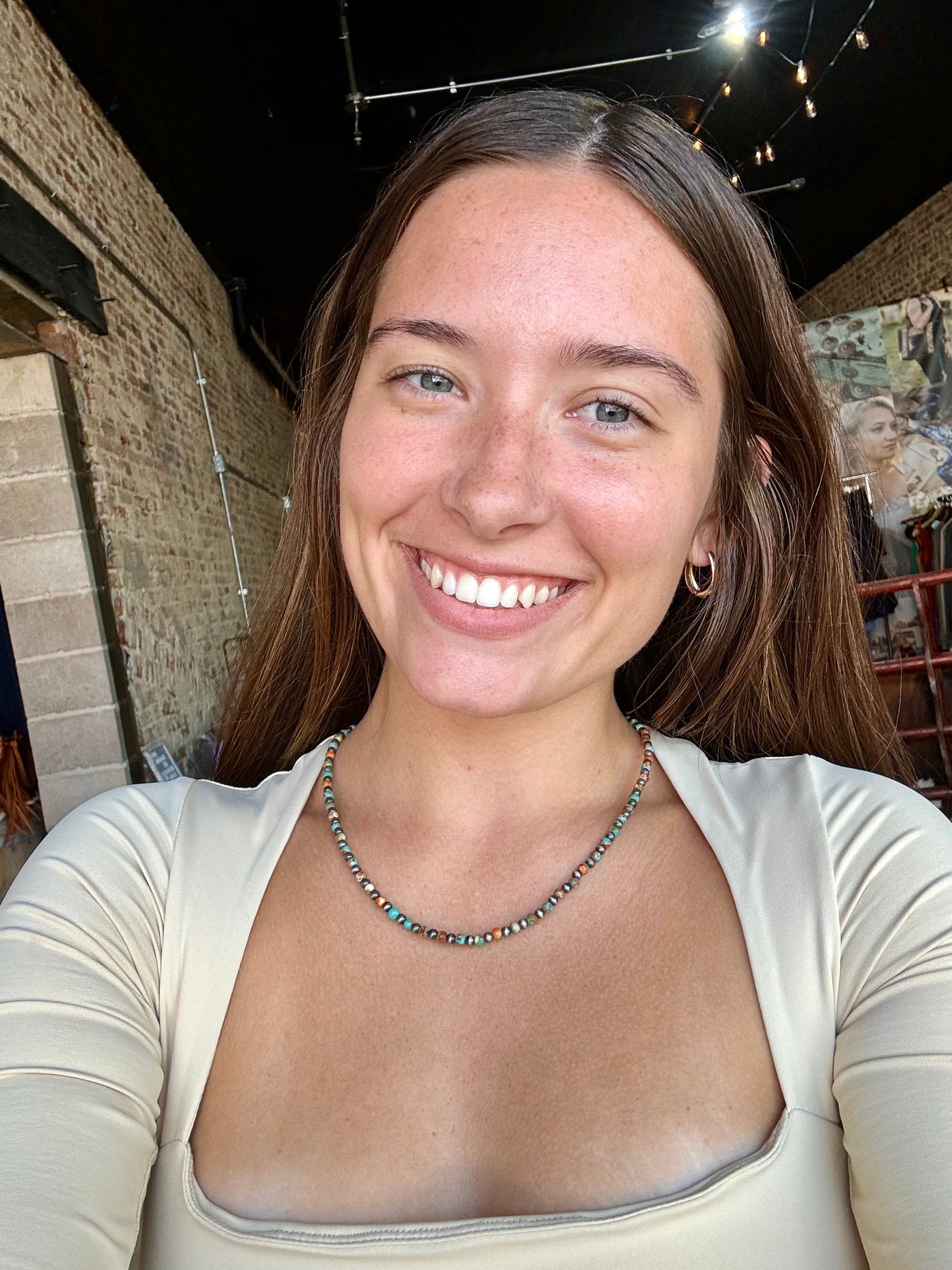 Western-style turquoise and Navajo pearl necklace with adjustable lobster clasp for layering or solo wear, modeled by Broker Leather employee.