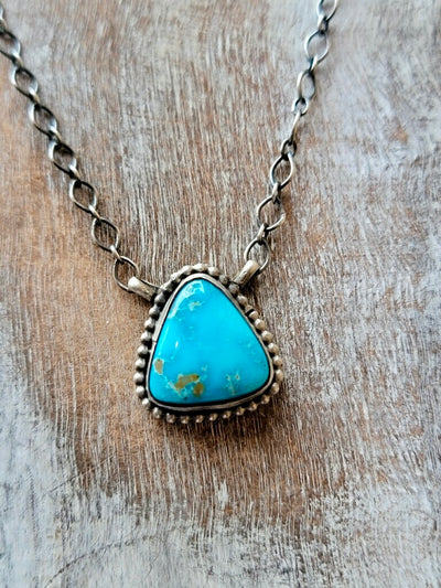 Close-up of Navajo-made turquoise pendant with intricate silver details.