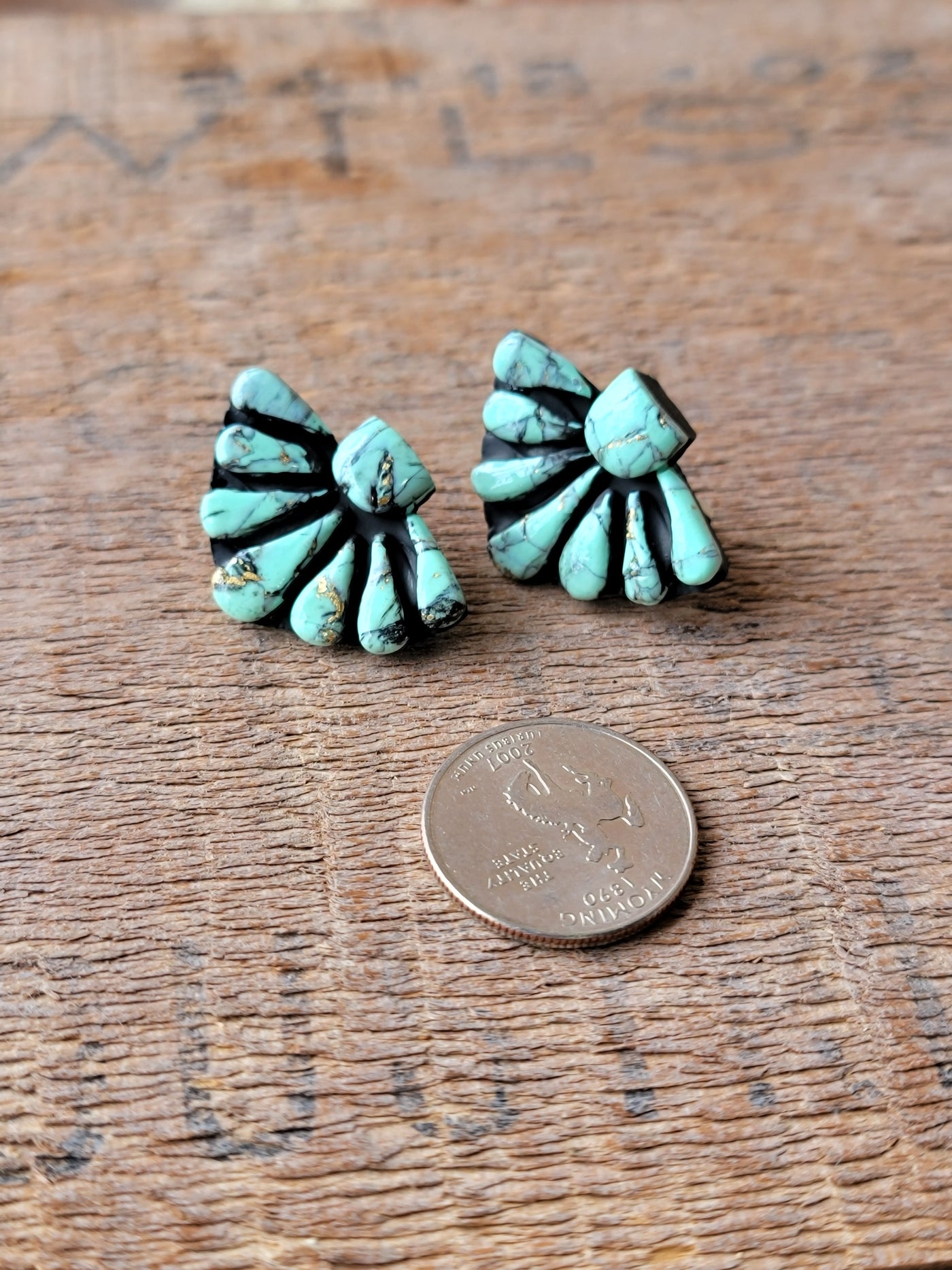 Flat lay of Ezra Clay Cluster Earrings displaying their one-of-a-kind craftsmanship and vibrant turquoise color next to a quarter for size relevance.