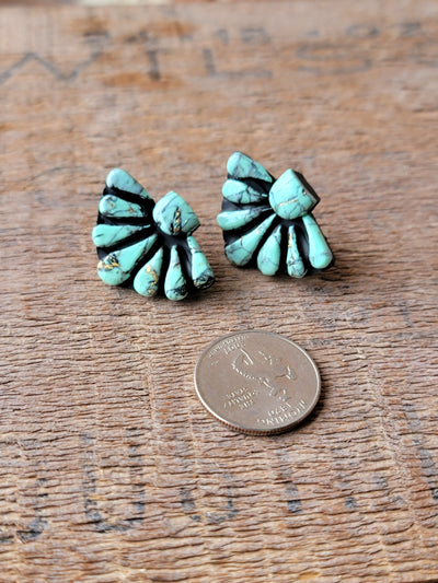 Flat lay of Ezra Clay Cluster Earrings displaying their one-of-a-kind craftsmanship and vibrant turquoise color next to a quarter for size relevance.