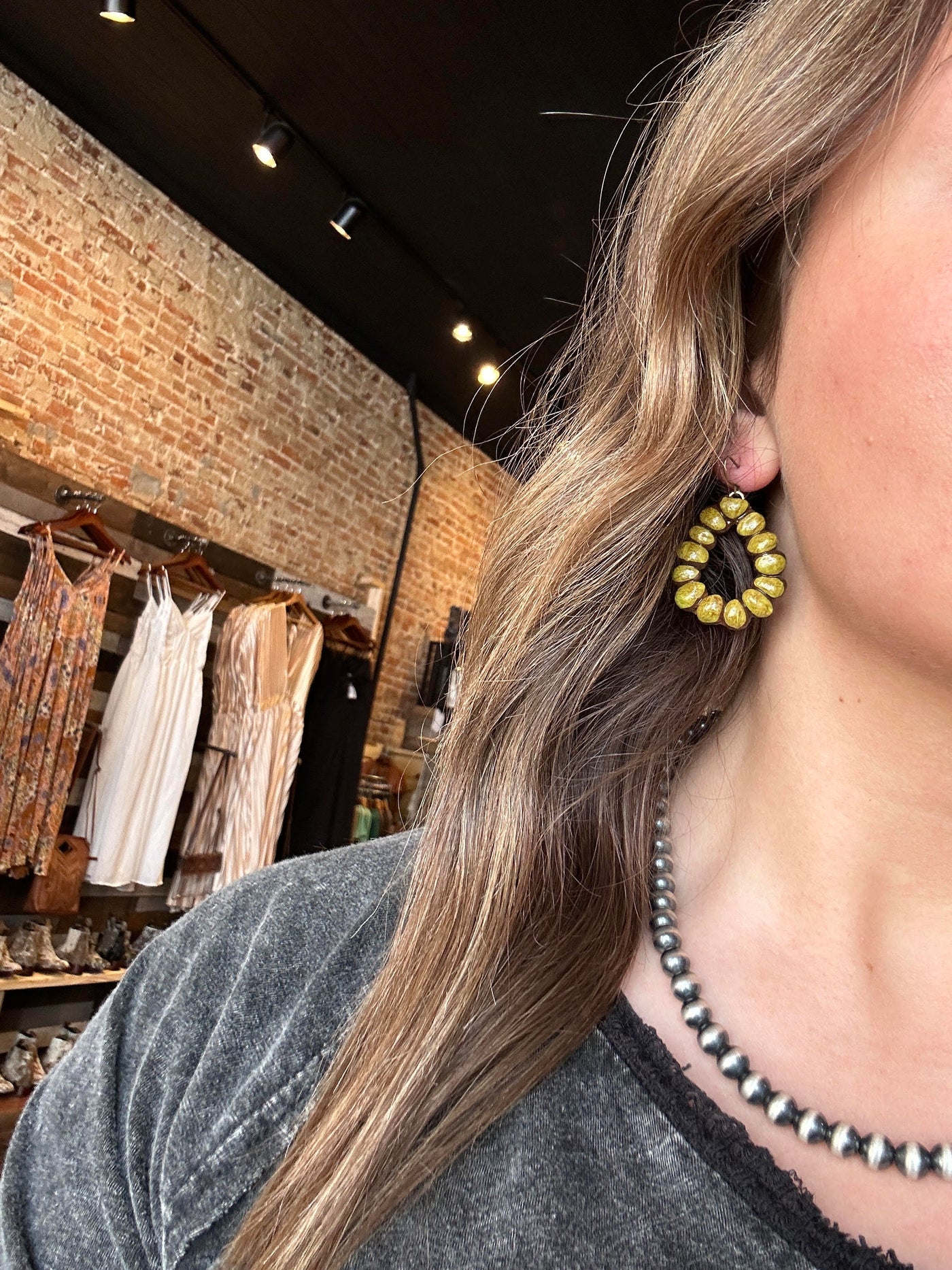 Model wearing Formula One Clay Teardrop Earrings in Army Green to show size relevance, styled for a bold yet natural Western look.