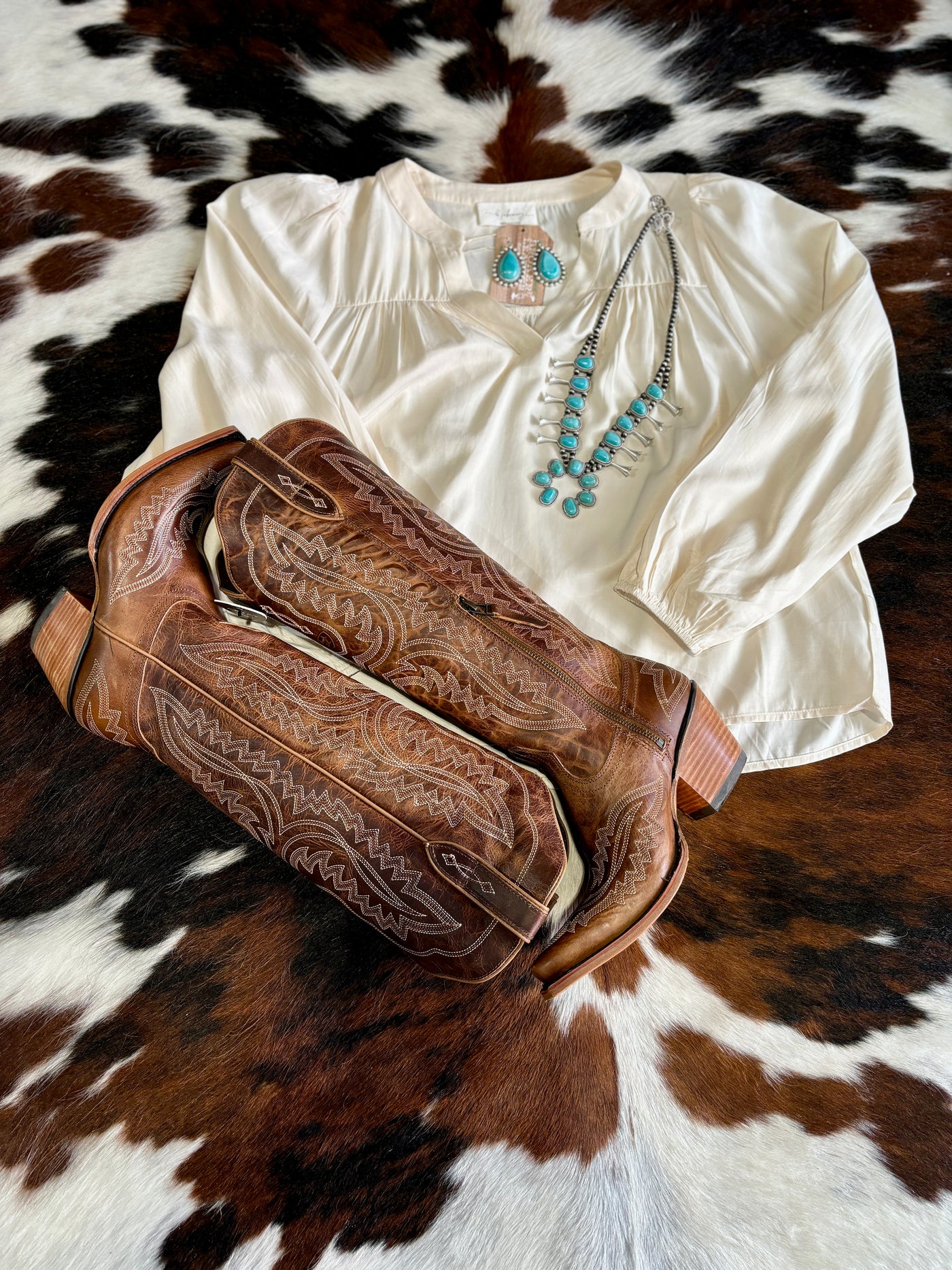 Our Alexandra Balloon Sleeve Blouse featured in a flatlay photo with Ariat Casanova Boots.