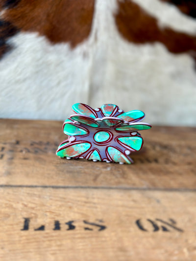 Side view of our Teri Turquoise Cluster Claw Clip with a wooden and cowhide backdrop.