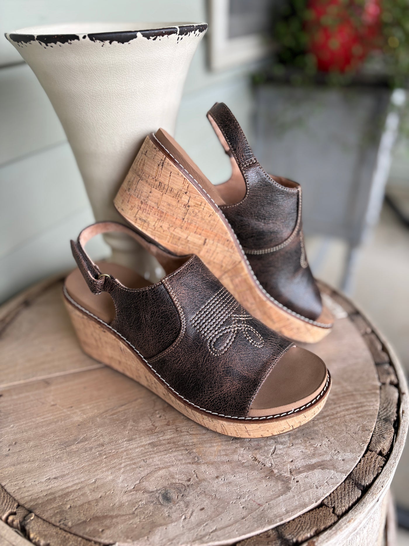 Brown wedge sandals on a wooden surface with a blurred background