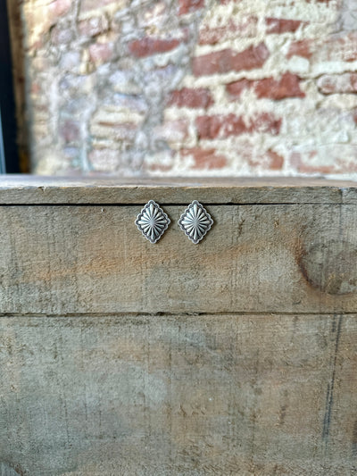 Our brand new Dawson Diamond-Shaped Concho Earrings hanging on a wooden box.