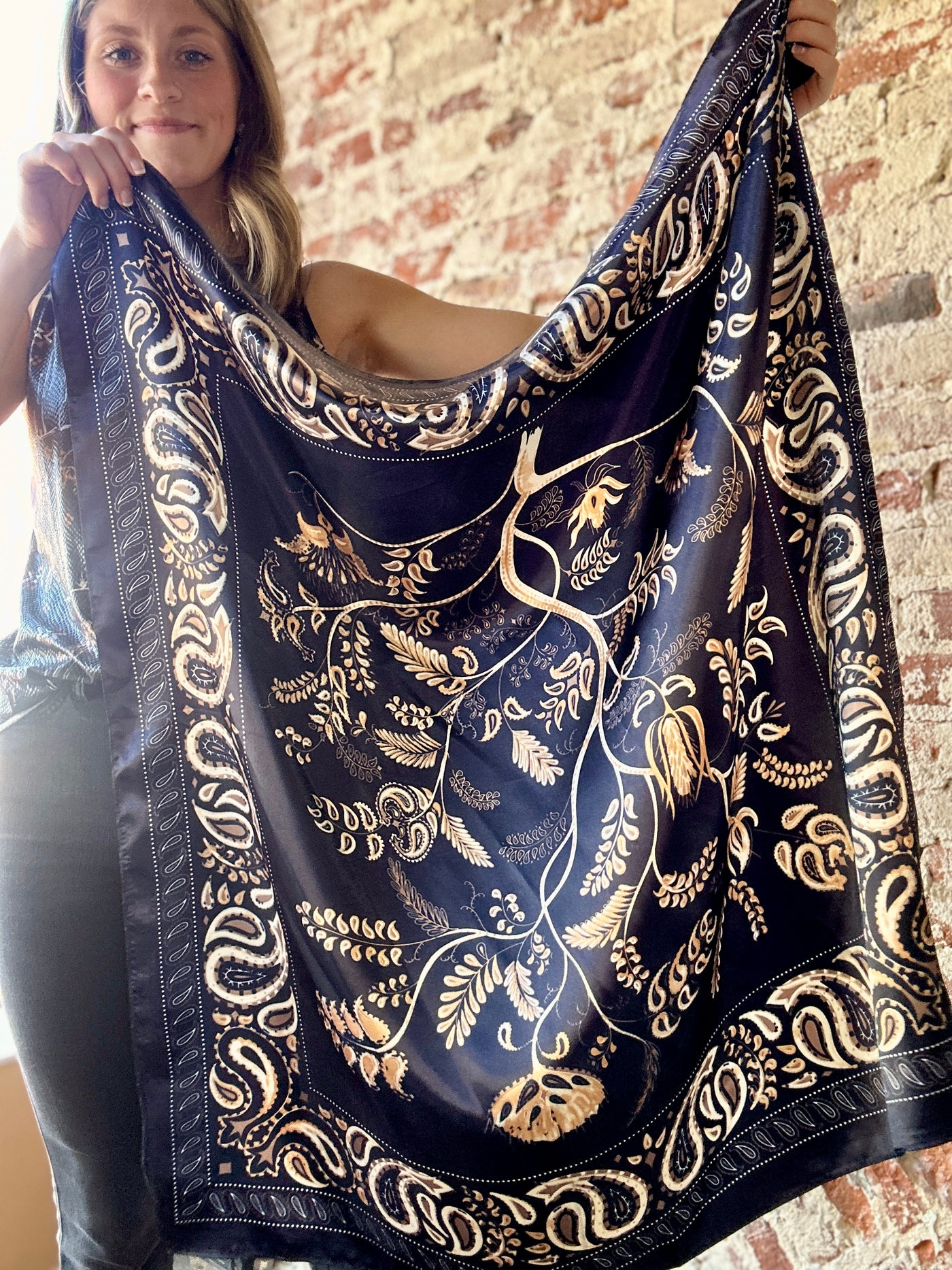 Woman holding up the Kiersten Navy Paisley Wild Rag to show the complete scarf pattern.