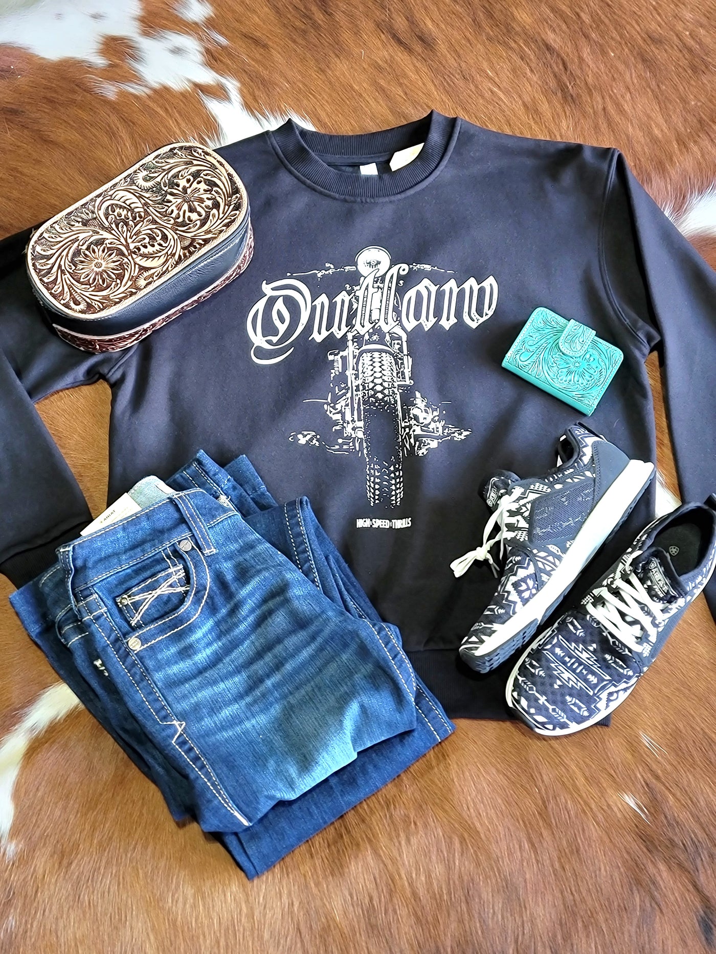 Flatlay of Western Boutique Aztec Ariat Fuse Western Sneakers For Women in Black & White and a black crewneck with an Outlaw Motorcycle.